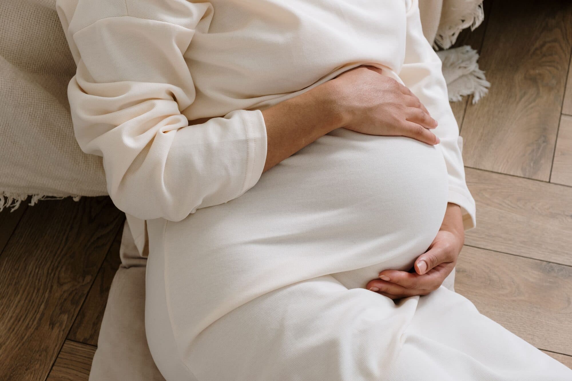 A woman cradling her belly with both hands