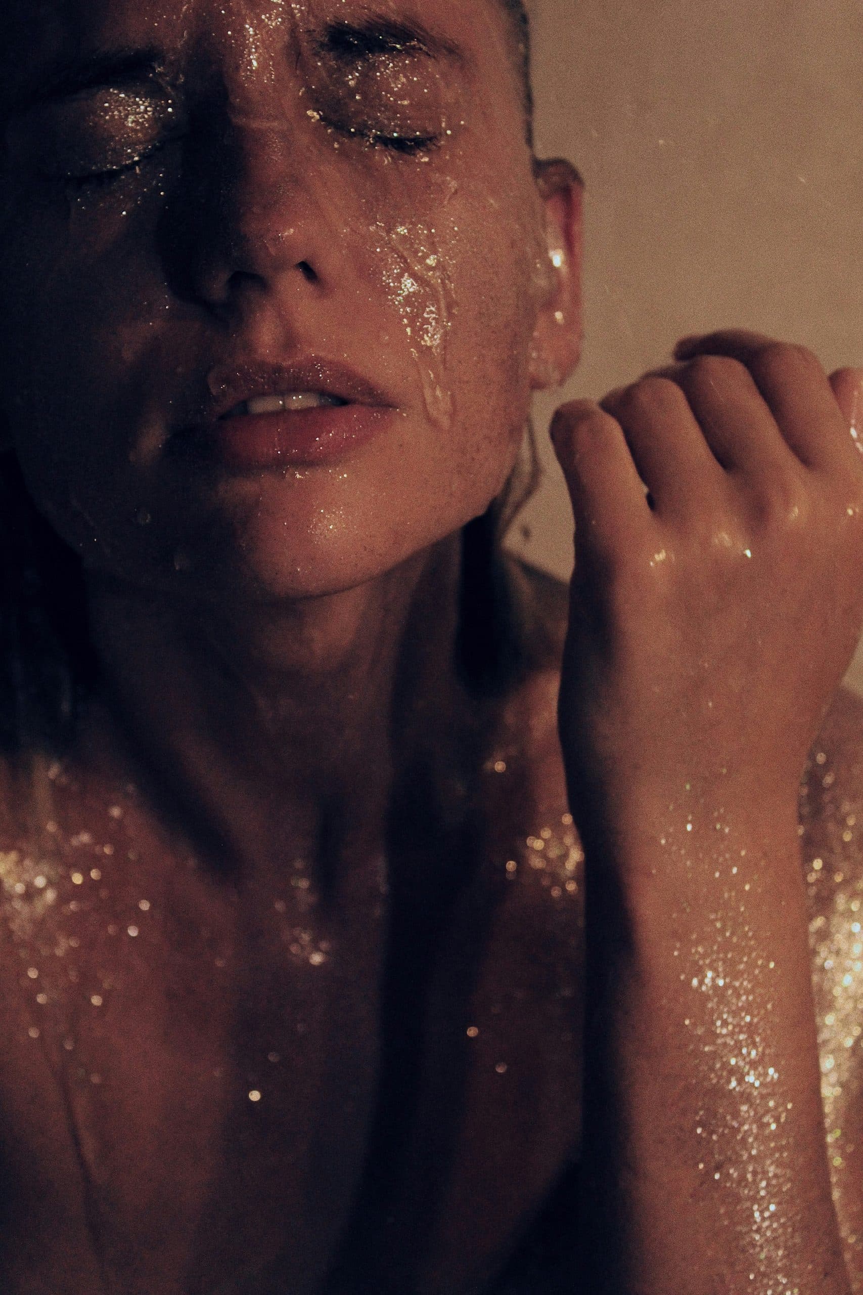 A woman with her eyes closed, her skin catching gold light