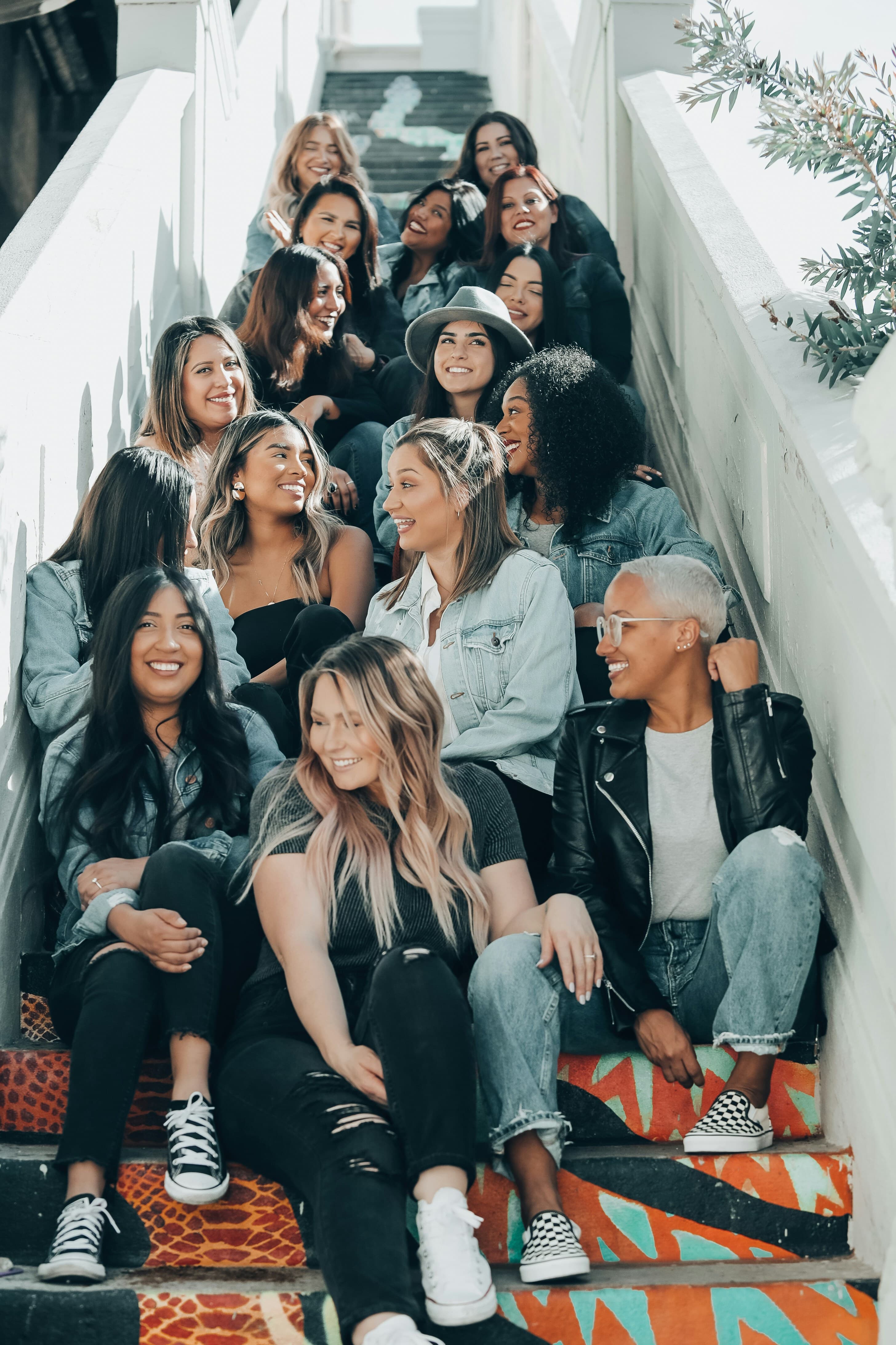 A diverse group of women sitting together on outdoor steps, smiling and laughing
