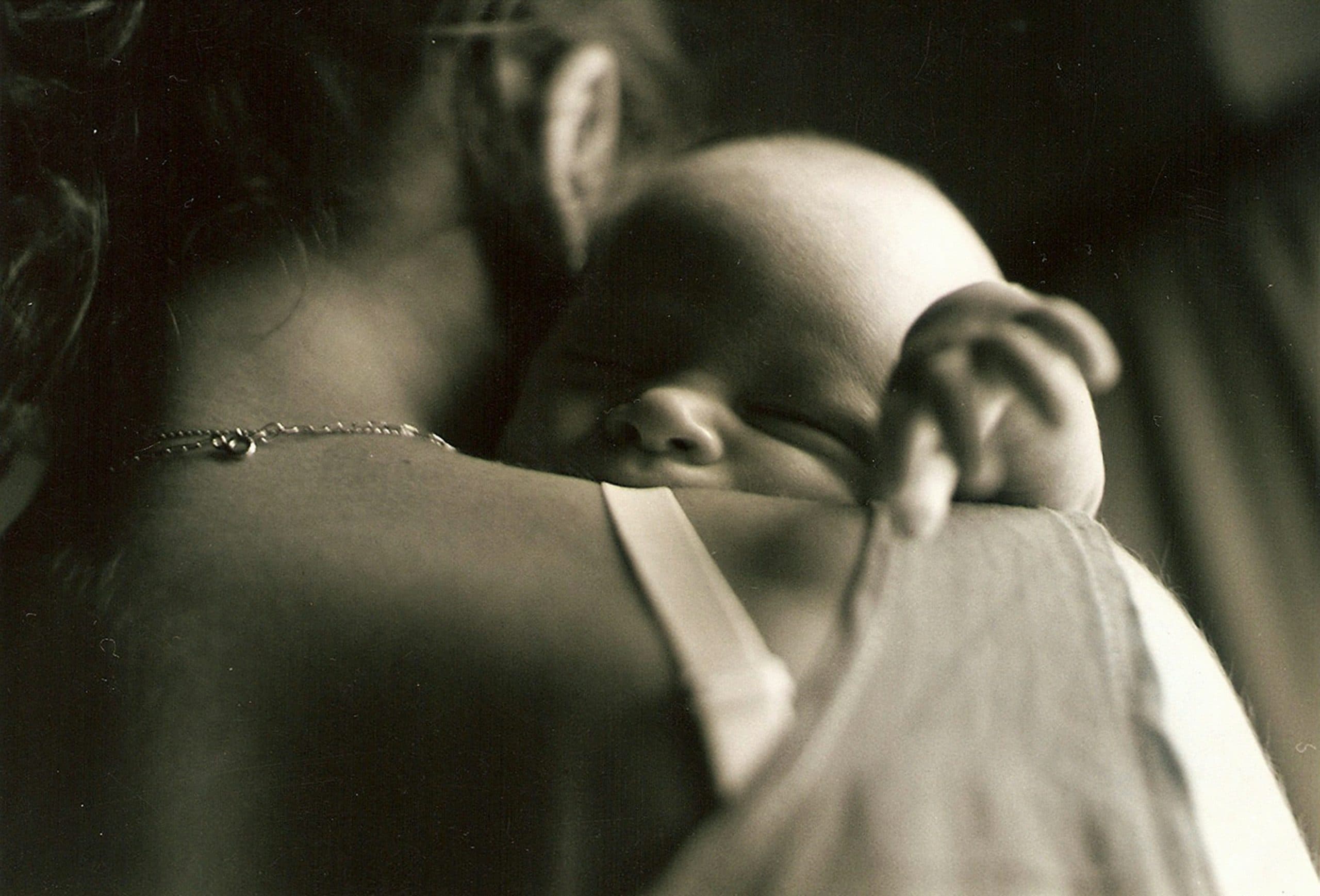 A newborn asleep against their mother's shoulder