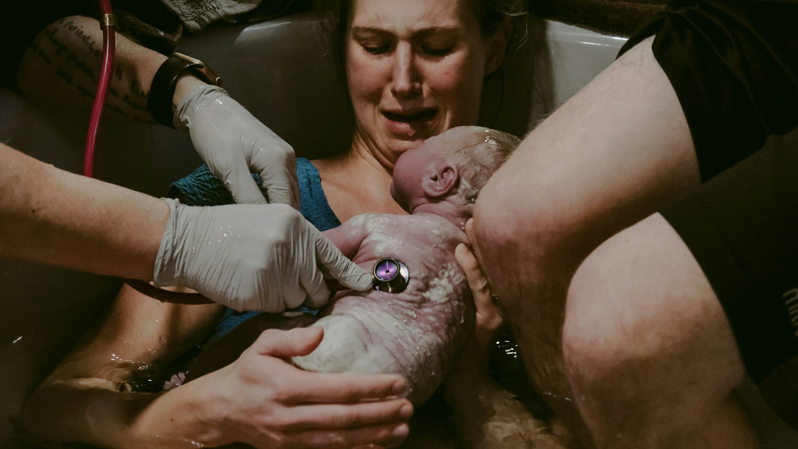 A baby lifted onto their mother's chest in the moment after birth